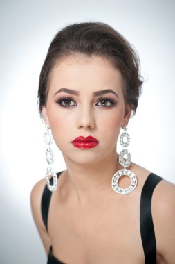 Saç ve makyaj - güzel kadın sanat portre Küpeli. Zerafet. Jewelries Studio'yu hakiki doğal esmer. Kırmızı dudaklar ve yaratıcı makyaj ile çekici bir kadın portresi