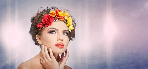 Portrait de belle fille en studio avec des roses jaunes et rouges dans les cheveux et les épaules nues. Jeune femme sexy avec un maquillage professionnel et des fleurs lumineuses. Coiffure créative et maquillage, plan studio — Photo