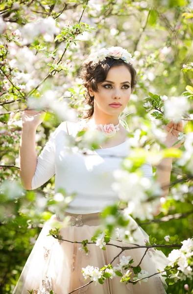 Porträtt av vacker flicka poserar utomhus med blommor av körsbärsträd i blossom under en ljusa vårdag. Attraktiv brunett kvinna med blommor tillbehör i orchard, våren skott — Stockfoto