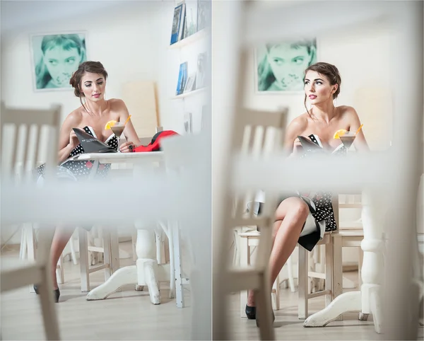 Fashionable attractive young woman sitting in restaurant. Beautiful brunette posing in elegant scenery with a martini glass on the table. Pretty female relaxing with a magazine, indoor shot. — Stock Photo, Image