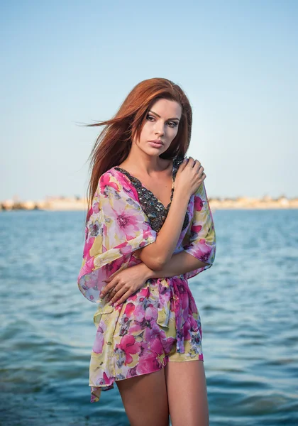 Menina de cabelo vermelho sexy nova em blusa multicolorida posando na praia. Mulher atraente sensual com cabelo longo, tiro de verão na costa do mar. Corpo perfeito feminino, conceito de férias turquesa backgroud água — Fotografia de Stock