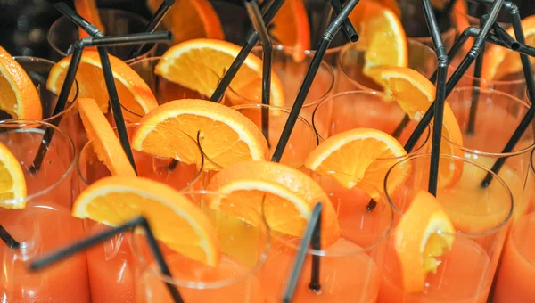 Bebidas frescas com fatias de laranja e palhas, de perto. Suco de laranja em copos com palhas, pronto para ser bebido — Fotografia de Stock