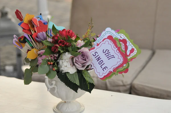 Buquê de flores frescas multicolorido e decorações de papel em um vaso em uma mesa e etiqueta com palavras ainda únicas. Arranjo de mesa de casamento para participantes individuais — Fotografia de Stock