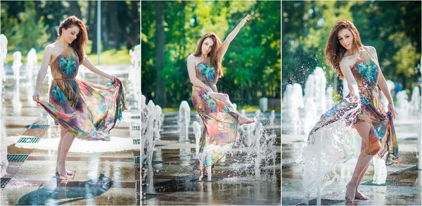 Attractive girl in multicolored short dress playing with water in a summer hottest day. Girl with wet dress enjoying fountains. Young beautiful happy female playing with outdoor water fountains. — Stock Photo, Image