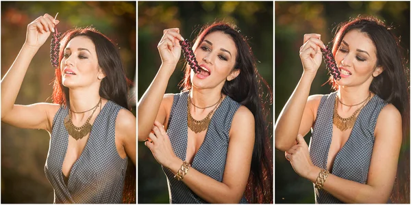 Mulher bonita em cinza posando no parque outonal segurando um grupo de uvas maduras. Jovem morena comendo uvas ao ar livre no outono. Longa mulher de cabelo escuro sorrindo segurando um monte de uvas verdes — Fotografia de Stock