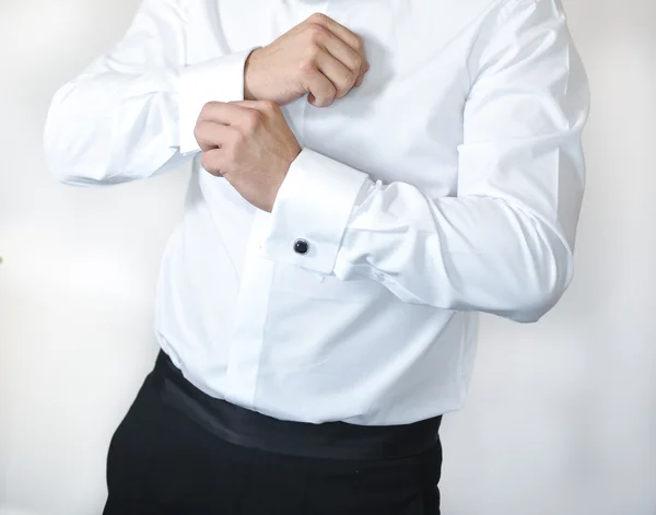 Um noivo colocando em botões de punho como ele se veste em roupas formais — Fotografia de Stock