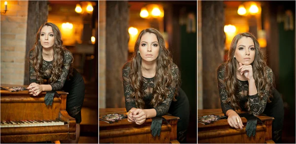 Young beautiful brunette woman in elegant black dress standing near a vintage piano. Sensual romantic lady with long dark hair in luxurious interior, daydreaming. Attractive girl posing indoors — Stock Photo, Image