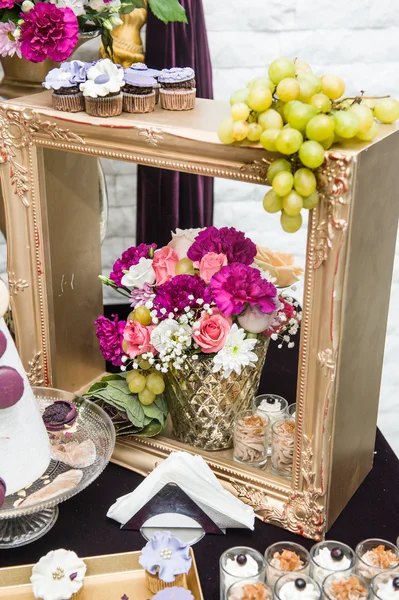 Decoration with pink, white and red flowers in golden wooden frame. Wedding decor with grapes and cookies. Fresh roses in luxurious frame. Elegant wedding decor idea on restaurant table. — Stock Photo, Image