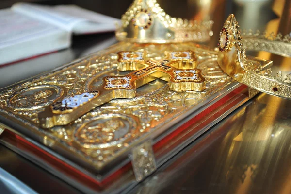 Cruces, anillos y coronas de oro sobre la mesa en la iglesia.Celebración de la boda — Foto de Stock