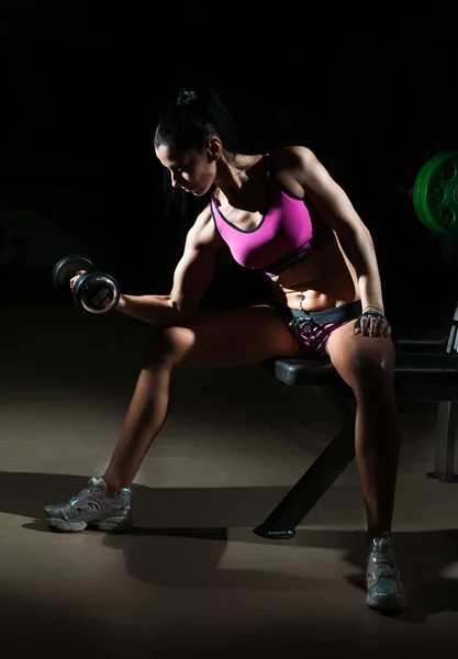 Linda morena levantando alguns pesos e trabalhando em seus bíceps em um ginásio. Mulher de fitness a fazer exercício. Menina desportiva fazendo exercício no centro de fitness. Linda morena tonificando seus músculos no ginásio — Fotografia de Stock