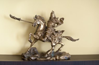 Knight on horseback miniature. Metallic knight holding a sword on the back of a horse clipart