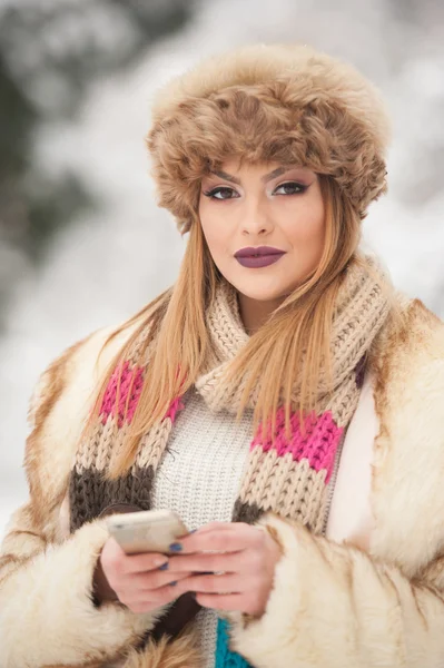 Atractivo joven caucásico adulto con gorra de piel marrón. Hermosa chica rubia con labios y ojos preciosos con sombrero de piel, tiro al aire libre. Maquillaje - sensual pelo largo y claro retrato de arte femenino, temporada de invierno —  Fotos de Stock