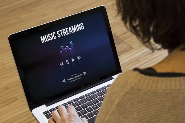 Женщина с ноутбуком музыка потоковое на экране — стоковое фото