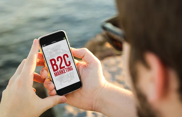 Man met telefoon aan kust met b2c marketing — Stockfoto