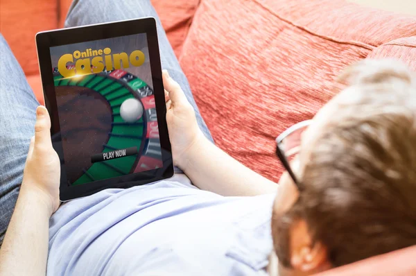 Hipster op sofa met online casino tablet — Stockfoto