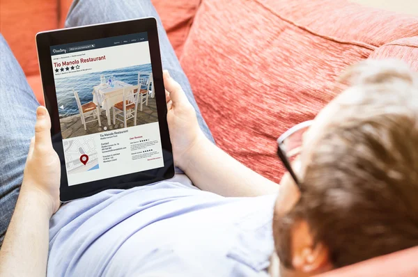 Hipster on sofa with online directory tablet — Stock Photo, Image