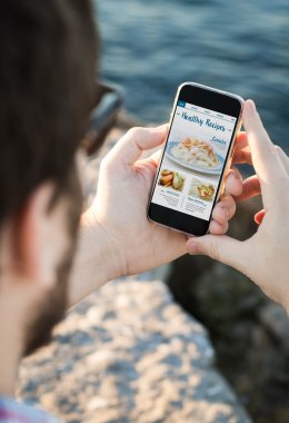 Sağlıklı yemek tarifleri ile akıllı telefon kullanan adam
