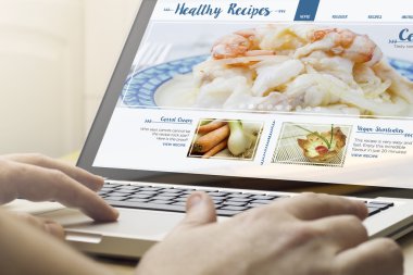 online yemek tarifleri ile dizüstü bilgisayar kullanan adam