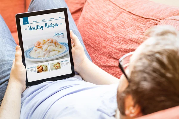 Hipster on sofa with online recipes blog — Stock Photo, Image