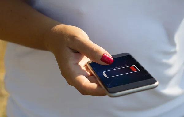 Женщина трогает смартфон с низким зарядом батареи — стоковое фото