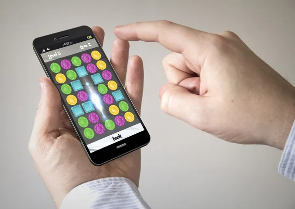 Man using smartphone with puzzle game on the screen — Stock Photo, Image