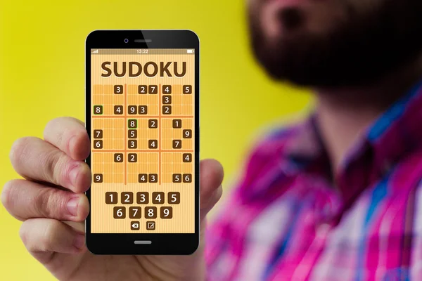 Hipster holding a smartphone with sudoku application — Stock Photo, Image
