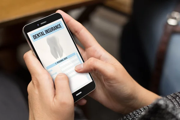 Mädchen nutzt Smartphone mit Zahnzusatzversicherung — Stockfoto