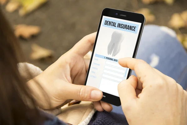 Mulher segurando smartphone com seguro dentário — Fotografia de Stock