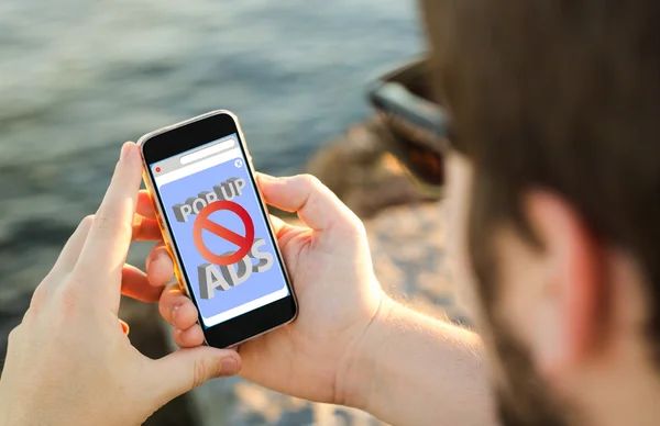 Homem usando seu telefone celular na costa com bloqueador de anúncios — Fotografia de Stock