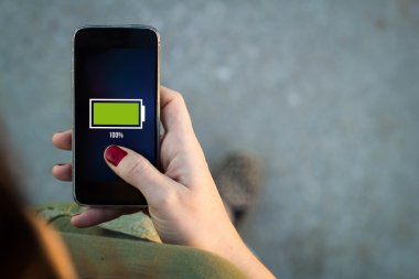 Woman walking with smartphone full battery on screen