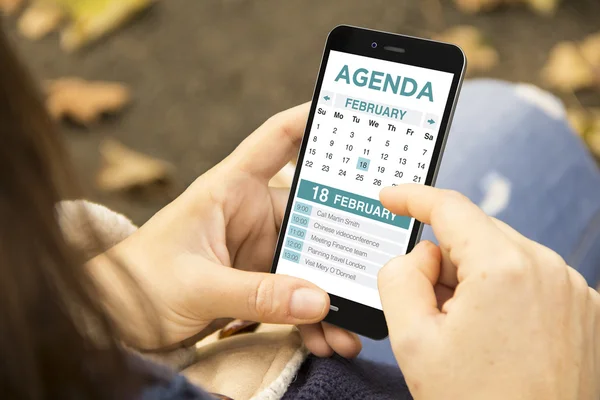 Woman holding smartphone and checking agenda — Stock Photo, Image