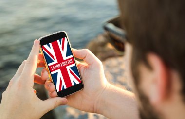 Man using his mobile phone on the coast to learn  english