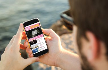 Man using his mobile phone on the coast to watch videos