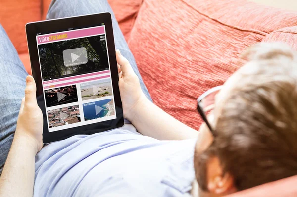 Hipster on the sofa with video streaming tablet — ストック写真