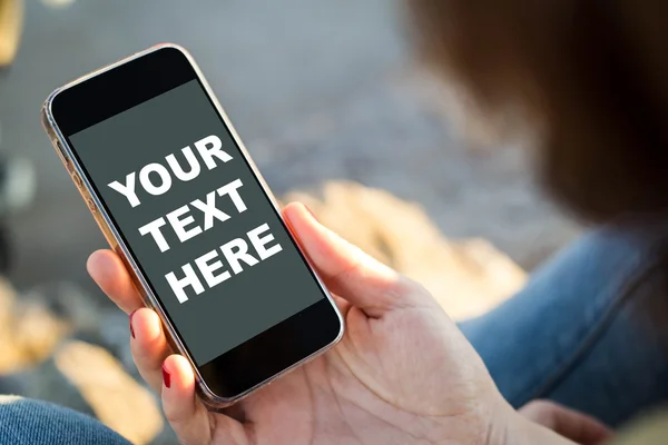 Woman sitting in the street holding her smartphone — Stock Photo, Image