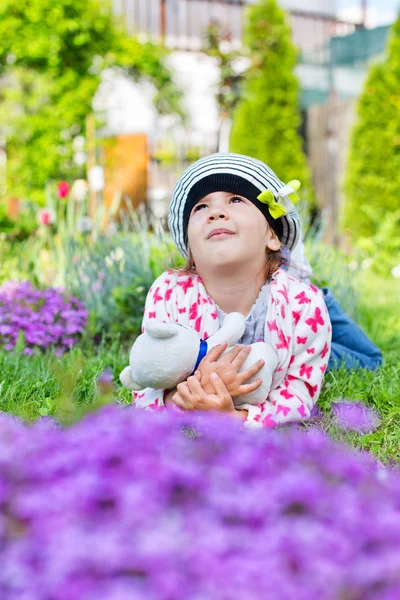 Nettes Mädchen spielt im Blumengarten — Stockfoto