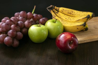 Üzümlü, yeşil, kırmızı elmalı ve muzlu, siyah arka planda meyve.