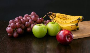 Üzümlü, yeşil, kırmızı elmalı ve muzlu, siyah arka planda meyve.