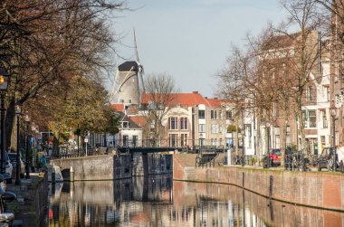 Schiedam, Hollanda, 7 Kasım 2020: Lange Haven (Long Harbour) kanalı boyunca yeni bataklığa doğru görüş ve arka planda tarihi yel değirmenlerinden biri