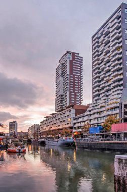 Rotterdam, Hollanda, 5 Kasım 2020: Modern yüksek apartman binaları ve Wijnhaven limanında yansıyan günbatımı gökyüzü 