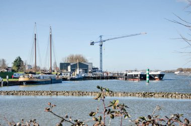 Puttershoek, Hollanda, 26 Şubat 2021: Çeşitli gemilerle, küçük sanayilerle ve Oude Maas Nehri 'yle kentin liman manzarası