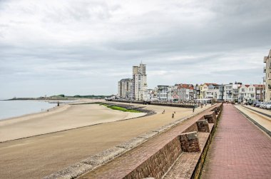 Vlissingen, Hollanda, 25 Temmuz 2021: Şehrin kumlu sahil şeridi boyunca bir asfalt yamacı, tuğladan bir deniz kenarı ve çeşitli stillerde mimari manzarası