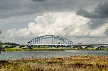 Zwolle, Hollanda, 10 Ağustos 2021: IJssel nehri, sel yatakları ve tarihi köprü üzerindeki dramatik bulutlar