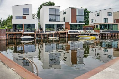 Zwolle, Hollanda, 3 Ağustos 2021: Pürüzsüz bir su kütlesine yansıyan dört modern villa.