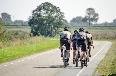 Sirjansland, Hollanda, 5 Eylül 2021: Schouwen-Duithe adasındaki düz arazide asfalt yolda bir grup hızlı bisikletçi