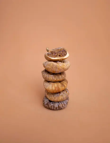 Kurumuş incirler tek tip turuncu arka planda bir yığın içinde yatıyor.