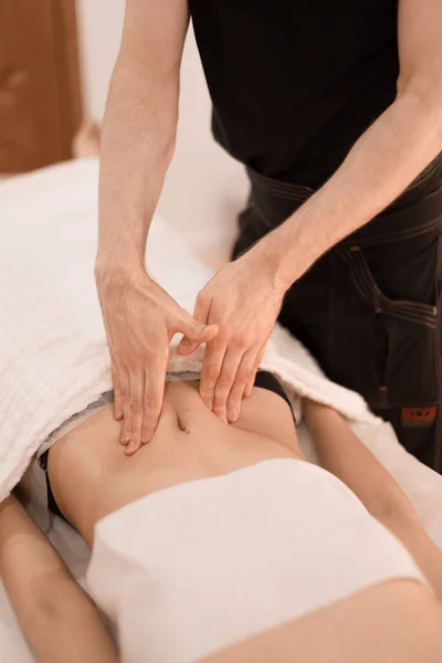 Bir adam spa salonundaki bir kıza masaj yapıyor.