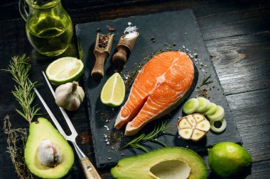 Somon bifteği kızartılmaya hazır koyu arkaplanda malzemeler var.