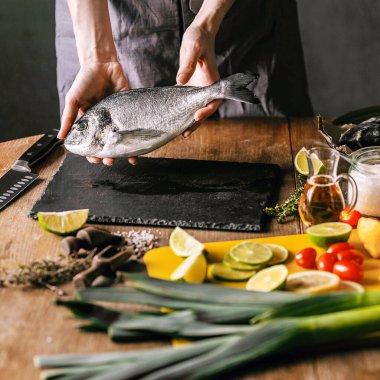 Kadın şef taze çiğ dorado balığı hazırlıyor.