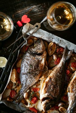 İki kişilik yemek konsepti. İki kadeh beyaz şarap, fırında balık..